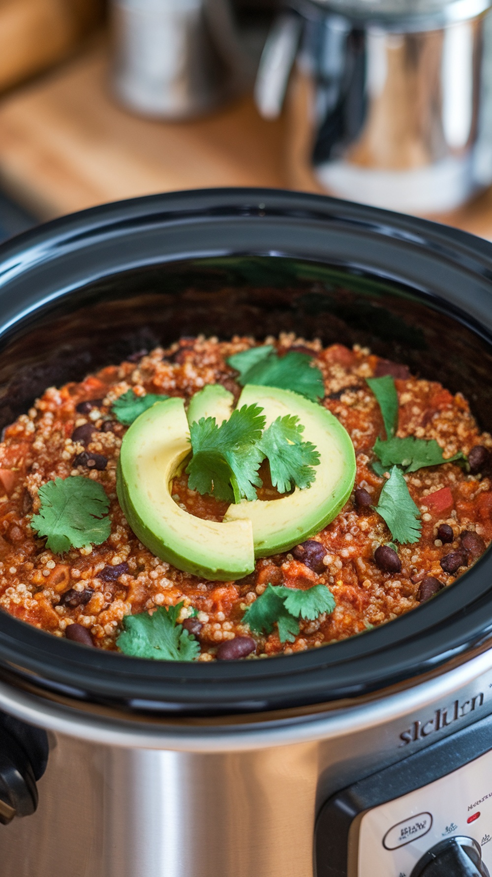 Bowl of quinoa and black bean chili topped with cilantro and avocado.